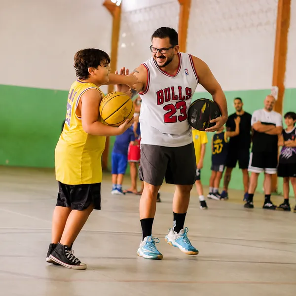 Professor comemorando com aluno durante aula de basquete do CDB
